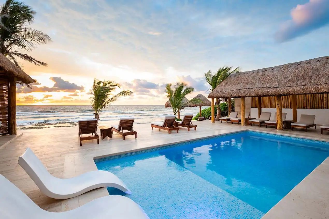 Bella Vita Tulum private pool with lounge chairs and beachfront view at sunset